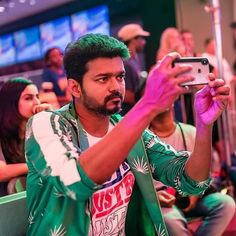 a man taking a selfie with his cell phone in front of him at an event