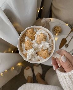 a person holding a white cup filled with cookies and whipped cream on top of it