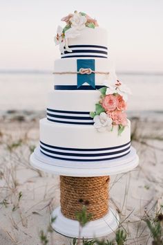 a white and blue wedding cake sitting on top of a rope