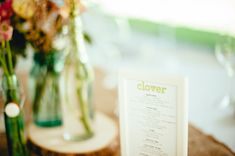 a menu sitting on top of a table next to vases with flowers in them