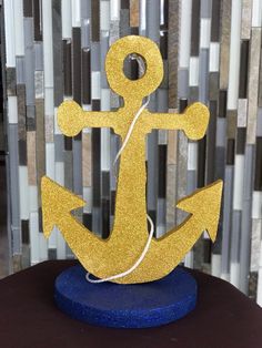 a gold glitter anchor on a blue stand