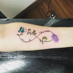 a woman's arm with a purple flower and an infinite sign tattoo on it