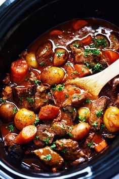 a crock pot filled with meat and potatoes, garnished with parsley