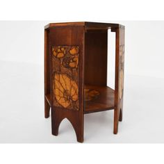 a wooden table with an intricate design on the top and bottom shelf, sitting against a white background