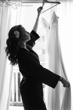 a woman is trying to hang her wedding dress on the clothesline in black and white