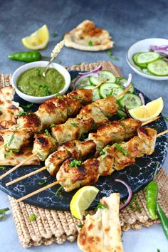 chicken skewers with cucumbers and sauces on a blue platter