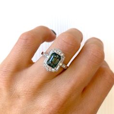 Blue Green Emerald Cut Sapphire Deco Halo Engagement Ring – Berlinger Jewelry Gia Certified Emerald Cut Sapphire Ring In Platinum, Green Sapphire Ring With Baguette Cut, Fine Jewelry Sapphire Ring With Moissanite In Emerald Cut, Emerald Cut Moissanite Sapphire Ring In Fine Jewelry Style, Gia Certified Square Cut Sapphire Diamond Ring, Emerald Cut Sapphire Ring With Baguette Diamonds, Gia Certified Rectangular Sapphire Ring For Anniversary, Gia Certified Sapphire Rectangular Ring, Gia Certified Emerald Cut Green Sapphire Ring