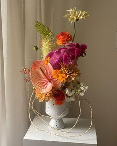 a white vase filled with lots of colorful flowers