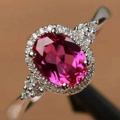 a ring with a pink stone and white diamonds on the bottom, in front of a brown background