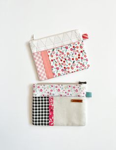 two zippered pouches sitting next to each other on top of a white surface