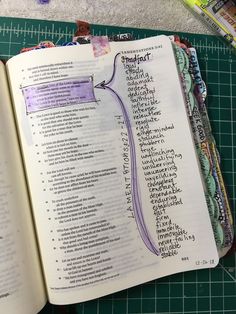 an open book with writing on it next to scissors and other crafting supplies sitting on a cutting board