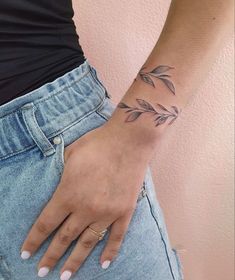 a woman's hand with a small tattoo on her left wrist and an olive branch in the middle