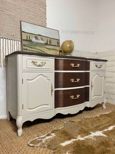 a white and brown dresser sitting on top of a rug next to a brick wall