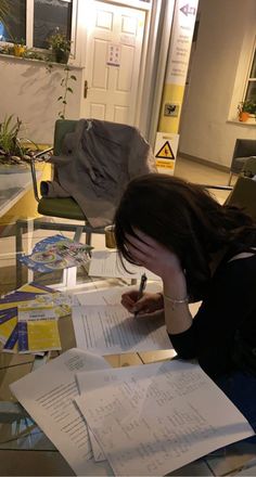 a woman sitting at a table writing on paper