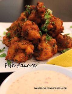 fried fish pakora served on a white plate with a lemon wedge next to it