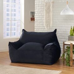 a black bean bag chair sitting on top of a hard wood floor next to a white brick wall