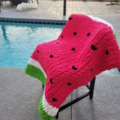 a watermelon blanket sitting on top of a chair next to a swimming pool