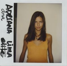 a woman with long brown hair wearing a yellow top and black writing on the wall