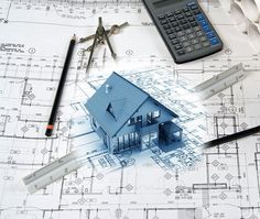 a blue house sitting on top of construction plans with tools and calculator next to it