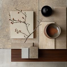 an arrangement of art work on display with a bowl, vase and other items in the foreground