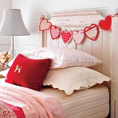 a bed topped with lots of pillows next to a lamp