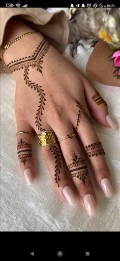 a woman's hand with henna tattoos on it and flowers in the background