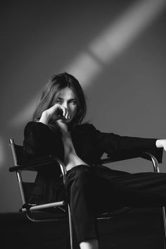 a woman sitting in a chair talking on a cell phone