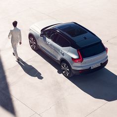 a man walking next to a silver car