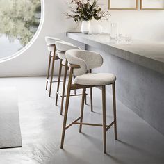 four bar stools are lined up in front of a counter with flowers on it