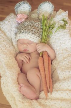 a baby is sleeping in a basket with carrots