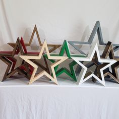 five wooden stars are lined up on a white tableclothed surface, each with different colors and sizes