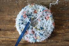 a piece of yarn with a blue crochet hook in it on a wooden surface