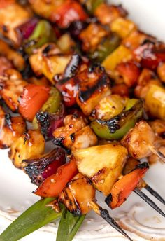 chicken and vegetable kabobs on a white plate with silver utensils next to them