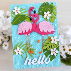 a card with two pink flamingos on it and some white flowers in the background