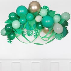 a bunch of balloons that are in the air with green and white decorations on them