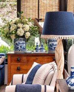 a living room with blue and white vases on the table, couches and lamps