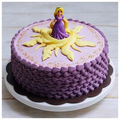 a purple cake with a princess figurine sitting on top of the frosting