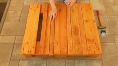 a person sitting at a wooden bench with their hands on the table and tools in front of them