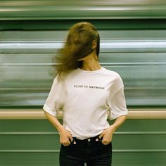 a woman standing in front of a train with her hands on her hips and looking at the camera