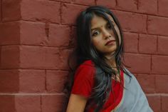 a young woman leaning against a brick wall