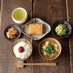 several bowls of food and chopsticks on a wooden table