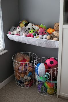 two baskets filled with stuffed animals on top of a white shelf next to a window