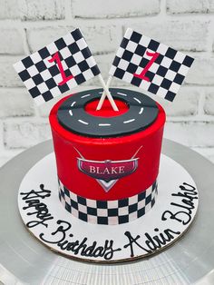 a birthday cake with checkered design and two flags on top, sitting on a silver platter