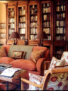 a living room filled with lots of furniture and bookshelves full of books on top of them