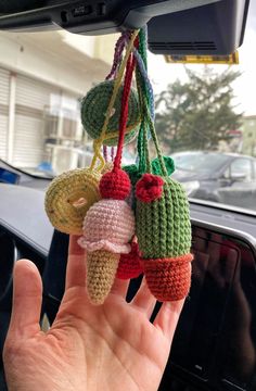 a hand is holding up some crocheted fruits hanging from a car dash board