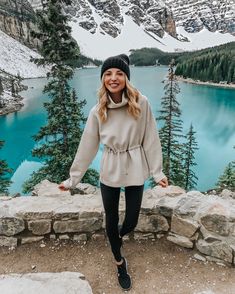 a woman standing on top of a mountain next to a lake