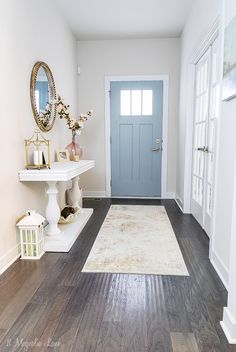 a white hallway with blue door and wooden floors