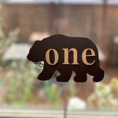 there is a wooden sign that says one on the front of it, with a bear