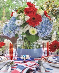 a vase filled with red, white and blue flowers on top of a table