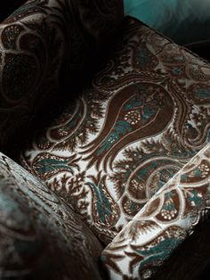 an upholstered chair with brown and teal paisley fabric on the armrests